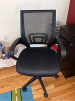 Front view of the adjustable office chair showing the black cushioned seat, black mesh backrest, and black armrests.