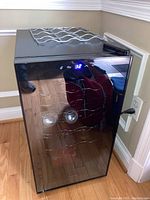 Front view of black Ivation wine fridge with glass door and digital temperature display showing '32'. Metal wire racks inside visible. Unit plugged into wall outlet.