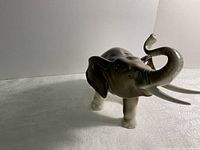 Porcelain elephant figurine viewed from front-left angle, showcasing raised trunk, tusks, and textured skin pattern