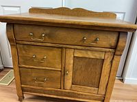 Front view showing drawers, cabinet door, brass hardware, and decorative top trim