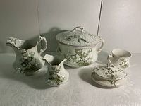 Full set of antique Wedgwood bathroom items showing the lidded chamber pot, washing pitcher, rinse jug, shaving mug, and soap dish in Hilda pattern.
