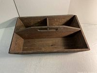 Top view of the wooden tool caddy showing three compartments separated by a vertical divider with a cutout handle.