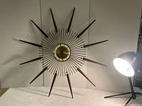 Full front view of clock showing brass and wood starburst design