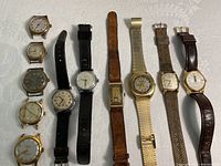 Photo showing all 9 watches laid out on a white cloth, displaying various styles and bands.