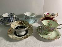 Front view of the five vintage teacup and saucer sets with various floral and ornate designs