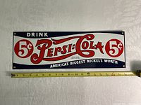 Front side of the vintage Pepsi porcelain enameled sign showing 5 cent Pepsi Cola logo and slogan with a tape measure indicating width about 17 inches.