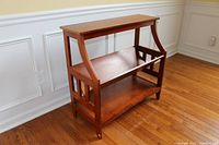 Front and side view of cherry wood bookcase showing the angled V-shaped center shelf and flat top and bottom shelves.