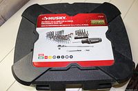 Closed black hard plastic case showing Husky brand label and set details