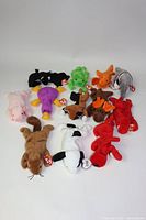 Photo showing full lot of 12 vintage Beanie Babies laid out flat on a white surface, showing tags and various colors and animals.