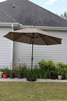 Full view of the 9ft brown patio umbrella with tilt and base with casters set up outdoors.