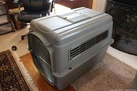 Side view of gray Petmate Sky Kennel pet carrier showing ventilation slats and metal door closed.