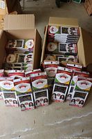 Two open brown cardboard boxes filled with multiple boxed packs of Upscale brand human hair weave extensions, showing 'Beach Curl 4PC' packs stacked and standing on the floor.