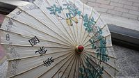 Top view of parasol canopy showing floral patterns and Chinese calligraphy on waxed rice paper