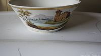 Side view of antique French porcelain bowl showing hand painted house landscape scene with tree and lake, gold rim.