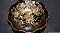 Top view showing the black ceramic bowl with detailed gold chrysanthemum floral pattern and scalloped edge