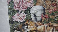 Close-up of the print showing a calico cat resting near a watering can, pink flowers, and terra cotta pots.