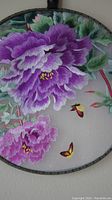 Close-up showing detailed purple floral embroidery with butterflies on silk fabric.