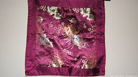 Front view of the silk pillow cover showing detailed embroidery and vibrant colors on a red-purple base fabric.