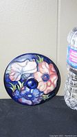 Top view of Moorcroft ceramic lid showing detailed floral pattern in multiple colors and central knob.