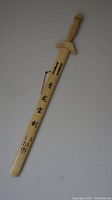 Full length view of natural bamboo/wood sword with black Asian characters on the scabbard