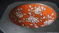 Top view of the ceramic bowl showing orange background with white floral designs in the pewter casing