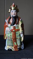 Front view of the hand-painted porcelain Cao Guojiu figurine showing detailed facial features, colorful traditional robes, and the items held.