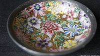 Close-up of the hand painted multicolor floral interior of the small bowl with pewter rim and base.