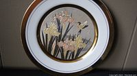 Photo showing the front of the round Chokin plate featuring iris flowers and dragonfly motif with gold accents.