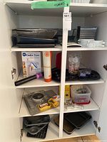 Shelf with various pans, muffin pans, cookie press, and dog bone cookie cutters.