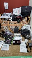 Overview of lot showing five cameras, rechargeable battery and multiple charger units