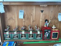 Hallmark Christmas ornaments including five reindeer and one Santa Claus in original boxes, Carlton snowperson in original red box on wood background.