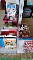 Overview of plastic storage bins filled with quilting books, fabric squares, and tools