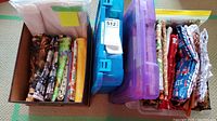 Overview of cardboard box and plastic containers filled with folded fabric pieces and storage bins