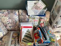 Overview of fabrics, books, and bins on floral couch with some sewing projects visible