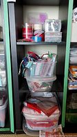 Shelf with fabric pieces in plastic bins and containers of beads and ribbon on shelves