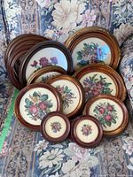 Overview of all framed needlepoint artworks and empty frames grouped on a floral chair