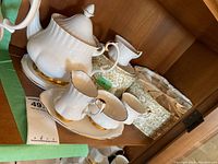 Teapot, sugar bowl, creamer, tray and storage box on shelf