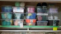 Three rows of clear plastic bins on shelf filled with yarn skeins
