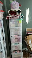 White plastic 5-drawer storage unit filled with yarn and topped with folded crocheted afghans