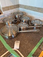 Overview of all five cookware pieces with lids arranged on countertop