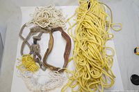Overview of five ropes including two yellow nylon and three white cotton blend/nylon ropes along with a brown leather safety belt.