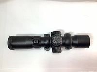 Top angled view of Excalibur Tact 100 scope showing the brand emblem on the adjustment turret and rings mounted on the tube.