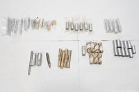 Overview photo of the entire lot showing multiple machine tool parts, handles, knobs, and small packaged bits laid out on a white surface.