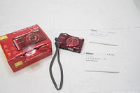 Photo showing Nikon COOLPIX L30 camera, original box, and two user manuals laid on white surface.