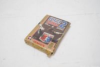 Plastic game cartridge with label showing RBI Baseball 2 title and design, resting on worn cardboard box.