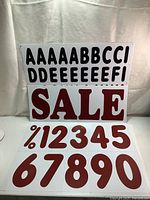 Photo of red 'SALE' letters and red numbers 0-9 plus % symbol on white background.