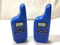 Front view showing two blue Midland T20 X-TALKER walkie talkies with LCD, buttons, and speaker grille.