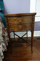 Front view showing two drawers with brass pulls and decorative side carvings