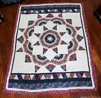 Full view of antique hand sewn star pattern quilt with multiple colors and floral fabrics.