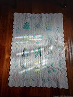 Full front view of the crib quilt showing appliqued figures and scalloped edges.